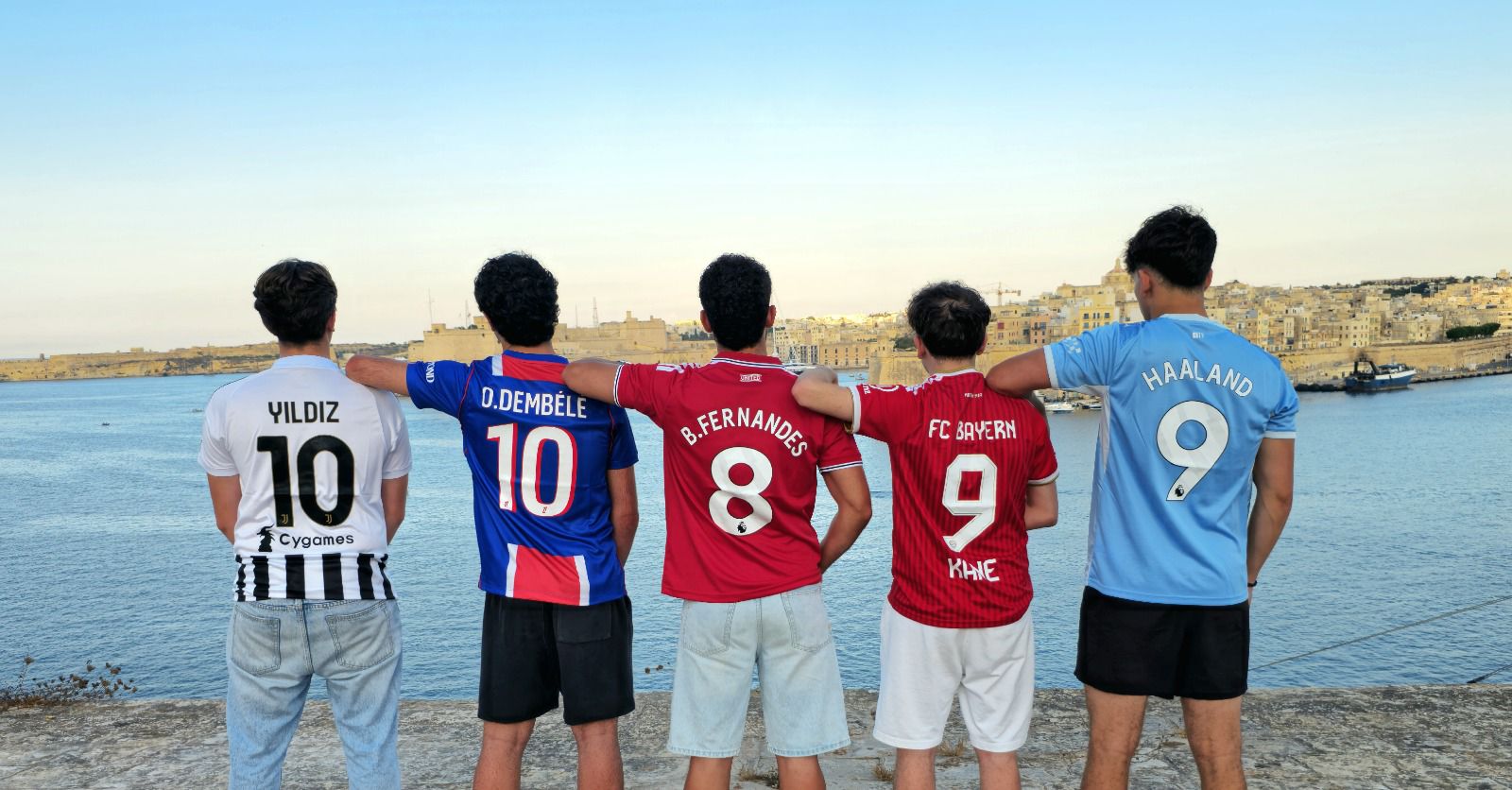Five friends in personalised football shirts looking out over the Grand Harbour in Valletta