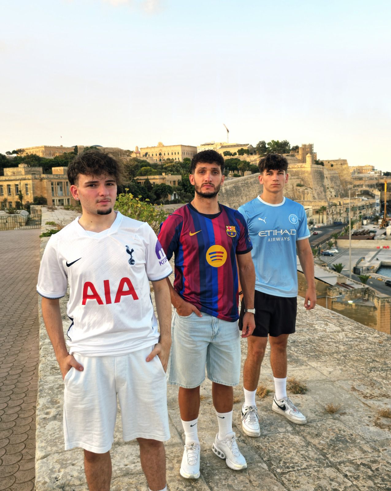 Three friends wearing Kit Studio shirts above the Valletta waterfront